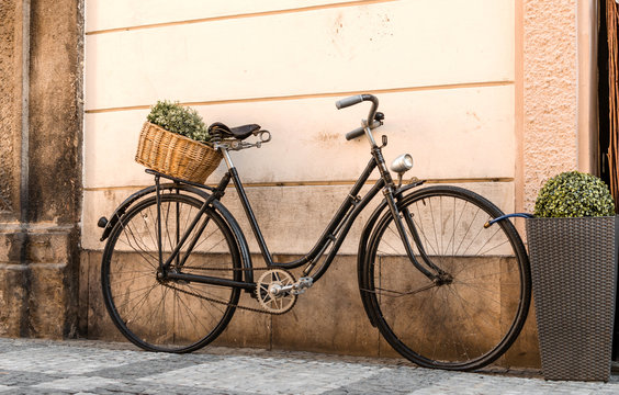 retro bicycle in front of a brick wall in the street with a basket of green flowers