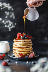 Pancakes with berries and maple syrup. Sweet homemade stack of pancakes