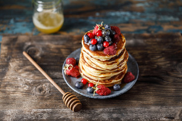 Pancakes with berries and maple syrup. Sweet homemade stack of pancakes
