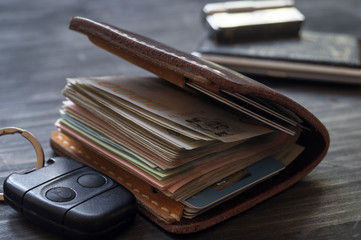 Old leather wallet full of money on wooden background