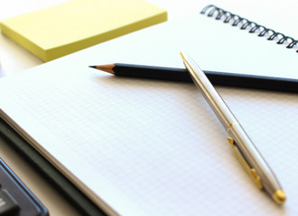 Pen on notebook and calculator isolated on white background