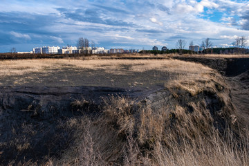 A deep ravine on the outskirts of the city of Ivanovo and high-rise buildings in the rays of the setting sun.