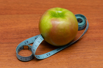 apple with old blue measuring tape on a wooden desk background