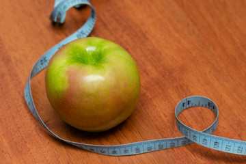 apple with old blue measuring tape on a wooden desk background