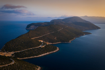 Ionian Sea and Lefkatos Lighthouse, sunset over the rocks on Lefkada Island, warm summer evening on the Mediterranean coast, aerial view from professional drone