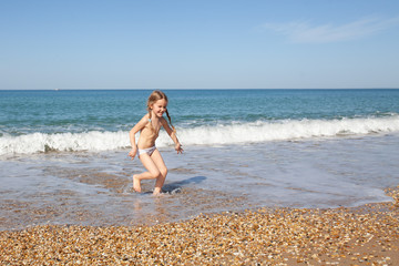 Happy and cheerful child runs on the seashore.