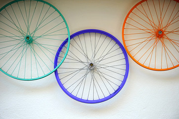 Old bicycle wheels colorful on the wall of a rental and repair shop, hipster decorative trend concept