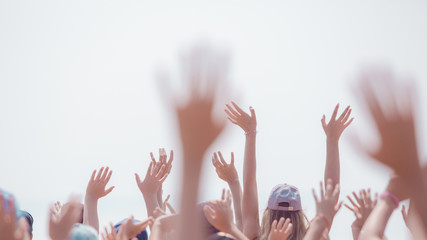group of happy young people with hands up to the sky