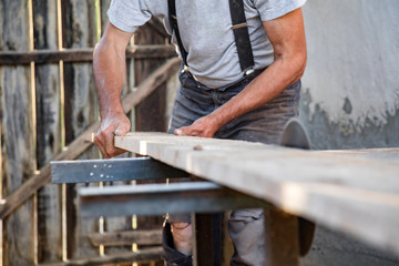 Carpenter using vintage electric circular saw.