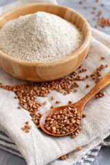 Buckwheat flour in a bowl and buckwheat grain in a spoon