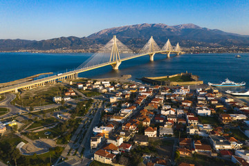 Aerial drone photo of world famous cable suspension bridge of Rio - Antirio Harilaos Trikoupis, crossing Corinthian Gulf, mainland Greece to Peloponnese, Patras with city view