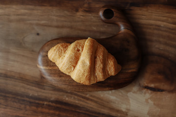 Fresh croissant lies on a wooden board on a wooden table.