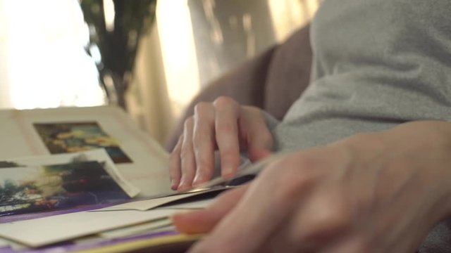 A woman looks at an old photo album, revises photographs and recalls the past.