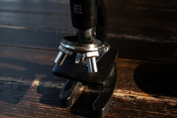 Black microscope on a dark wood floor in a laboratory