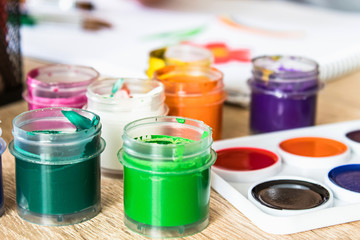 Watercolor paints and gouache in a jar on the table. Set for drawing, creativity and hobbies.