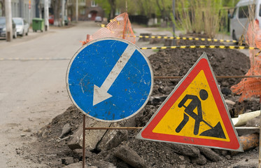road sign, detour, road repair on the background of the road and broken asphalt covering on the urban street