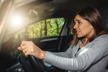 Scared caucasian woman driving car and risking a car crash.