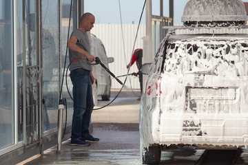 Male worker wash the car with high pressure washer