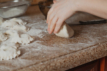 Hands knead piece of dough on granite table