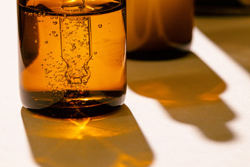 Brown glass bottles with oily skincare serum close up on white table