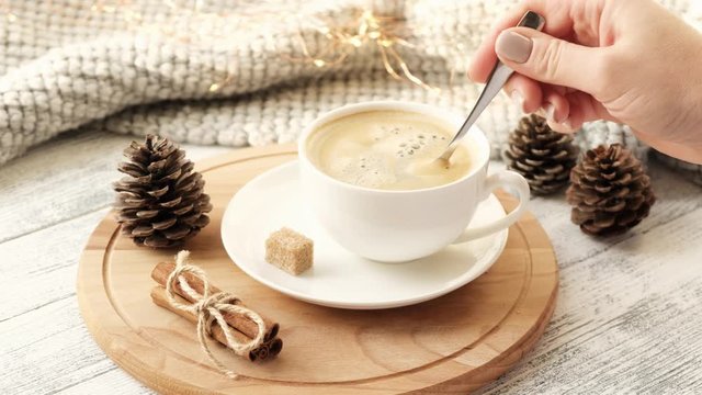 Female hand stir coffee in cup, slow motion. Cozy autumn composition. Hygge concept. 4K footage