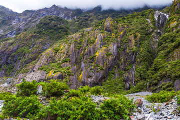Stones, Ice and green cliffs. Franz Joseph Glacier. South Island, New Zealand