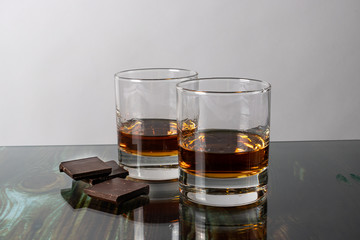 
Two glasses with whiskey and pieces of dark chocolate. Appetizer for alcohol, dear spirits.