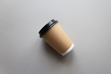 Coffee to go concept. Disposable craft cup with black plastic cover on a trendy grey background. Place for text. Flat lay style. Top view