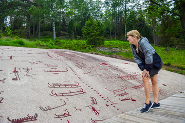 Tourists near rock carvings from Bronze Age, which are about 3000 years old. Tanum, Sweden.