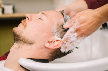 Obraz na płótnie Canvas Side view of man washing hair at barber shop