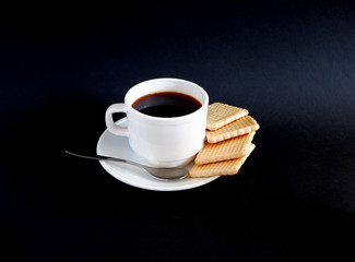 A Cup of black coffee and cookies on a black background. Suitable for mockups and advertising backgrounds