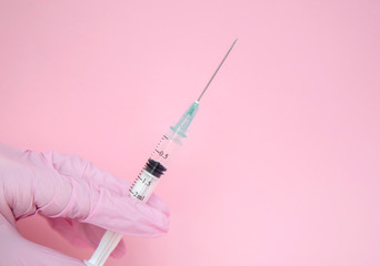 The doctor holds a syringe. Injection with medication. Medical worker in pink gloves. Vaccine in a...