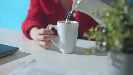 Office worker pour water from a kettle. Slowmotion
