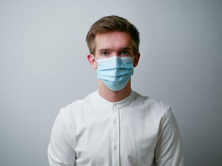 Man wearing a blue protective face mask against coronavirus. Medical staff preventive gear. White background.