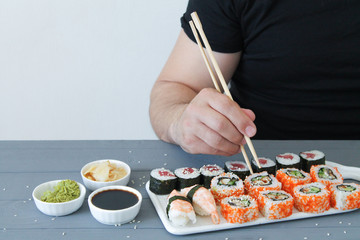 Side view of man hand with chopsticks eating sushi food at Japanese restaurant