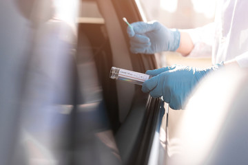Coronavirus test and person wearing gloves next to a car - obrazy, fototapety, plakaty
