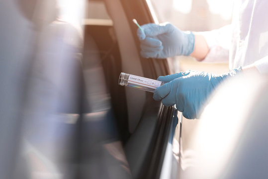 Coronavirus test and person wearing gloves next to a car