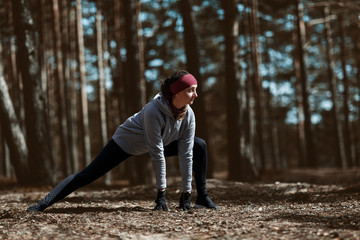 Girl does warm-up before exercising. Running in the pine forest.