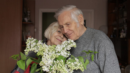 Portrait of a happy grandfather and grandmother. Grandma embraces gandpa