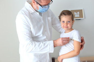 Fototapeta premium The doctor measures the temperature of a sick child