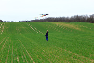 Boy launches a kite in a field in spring.