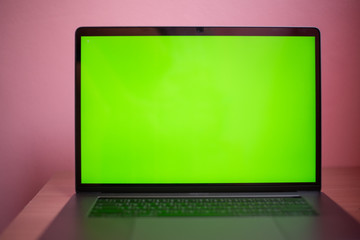 Laptop with green screen on table in work space concept.