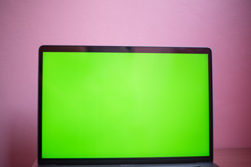 Laptop with green screen on table in work space concept.