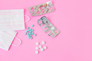 medical protective fabric masks and medications tablets on a pink background