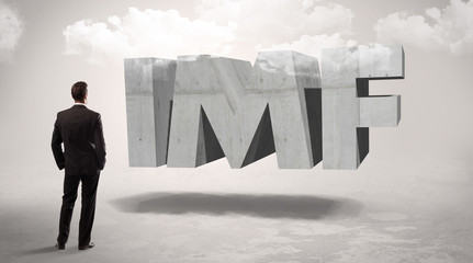 Obraz premium Rear view of a businessman standing in front of IMF abbreviation, modern technology concept