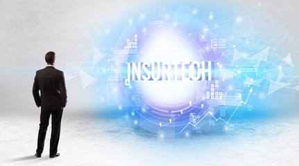 Rear view of a businessman standing in front of INSURTECH inscription, modern technology concept