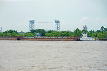 towboat pushing barges and industrial lock in new orleans