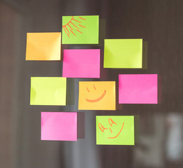 Close-up of sticky multicolored notes on a glass wall in the office. Horizontal photo.