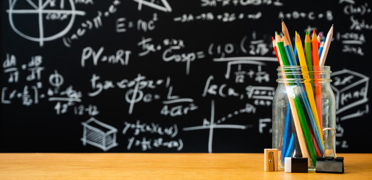 Education background concept. Stationery in glass jar color pencil, compasses tool, scissors, rulers, sharpener On chalkboard with the Mathematical formula background.