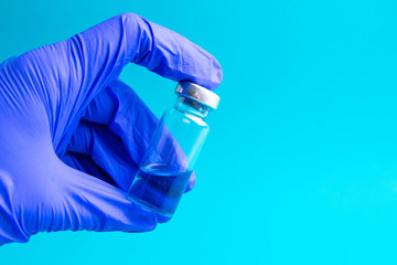 Vial with cure Covid-19. Doctor, nurse or scientist hand in blue gloves holds a vaccine coronavirus